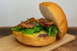 Bacon cheeseburger with open bread, showing bacon, arugula, patty and cheese.