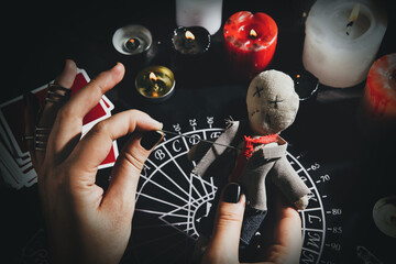 Wall Mural - Woman stabbing voodoo doll with needle at table, closeup. Curse ceremony