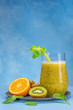 Glass of green spinach, orange, ginger and kiwi healthy smoothies.