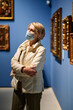 © JENOCHE - pensioner woman watching at art collection exhibition in museum