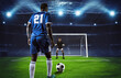 Soccer scene at night match with player in blue uniform kicking the penalty kick