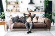 © Kateryna - Satisfied relaxed young indian man chilling on sofa in living room, smiling. Handsome arabian guy have rest at home, after laptop distant work, dreaming about vacations, throwing his hands behind head