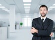 © BillionPhotos.com - Smiling young businessman with arms crossed in office background