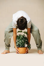 Boy Picking Up A Potted Plant From The Floor, Bending Forward