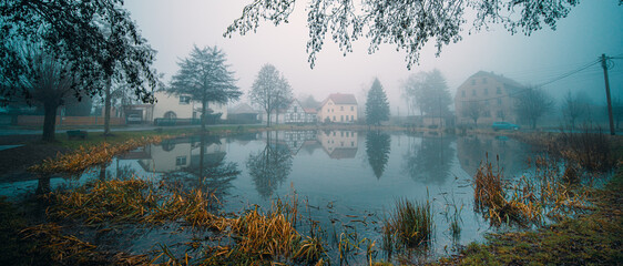 Wall Mural - House in a German village with reflection in a pond or lake