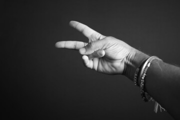 Canvas Print - A grayscale shot of a male hand making a victory sign on a dark background