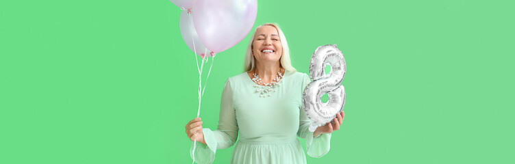 Wall Mural - Smiling mature woman holding air balloons on green background with space for text. International Women's Day celebration