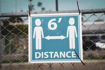 Social distance sign on construction site fence