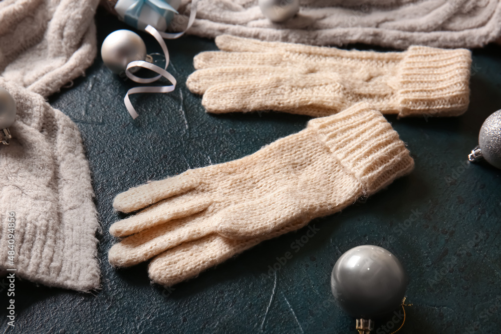 Warm gloves and Christmas decor on black background