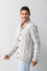 Wall Mural - Handsome African-American guy in knitted sweater on light background