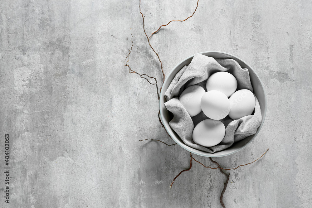 Bowl with Easter eggs and napkin on grunge background