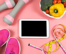 Flat Lay Of Blank Black Screen Of Computer Tablet, Pink Sneakers, Pink Dumbbells, Measuring Tape, And Vegatables On Pink Background. Healthy Lifestyle Concept.
