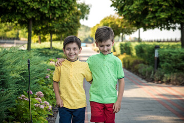 Wall Mural - childhood, hiking, family, friendship and people concept - two happy kids walking along forest path