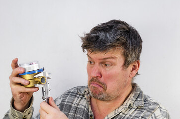 The surprised face of a man measuring a water meter with a calip