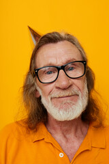 elderly bearded man wearing glasses with a cap on his head yellow background