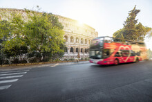 Street View With Motion Blurred Tourist Bus And Colosseum On Background In Rome. Traveling Italian Landmarks Concept. Idea Of Tourist Places And Attractions