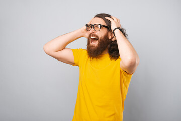 Wall Mural - Excited young bearded man in yellow t-shirt screaming and celebrating.