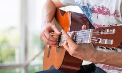 Canvas Print - Lifestyle concept. Young musician playing guitar in the living room at home on this weekend.