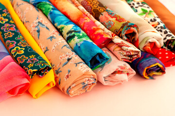 rolls of colorful fabric on a pink background. silk fabric for sewing. my textiles are piled up. bea