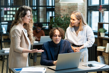 Poster - Three young confident colleagues discussing data on laptop screen while pregnant woman explaining main points to coworkers