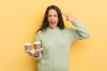 Wall Mural - young pretty hispanic woman looking unhappy and stressed, suicide gesture making gun sign. take away coffee concept