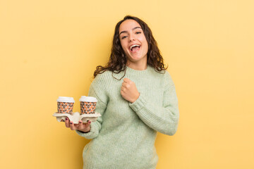 Wall Mural - young pretty hispanic woman feeling happy and facing a challenge or celebrating. take away coffee concept