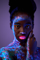 Beautiful extraterrestrial model woman in neon light. It is portrait of beautiful black model with fluorescent make-up, Art design of female posing in UV with colorful make up. Isolated