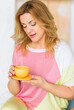 © ribalka yuli - A beautiful mature woman in a pink sweater and yellow pants poses for the camera with a tea cup.