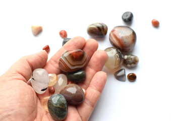 Wall Mural - Multi-colored minerals of semi-precious stones. Agates of different sizes in a female hand. Botswana agate