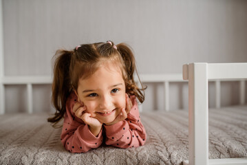 little girl is lying on her bed and smiling.