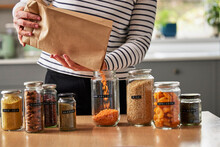 Woman Saving On Packaging By Filling Recycled Jars To Store Dried Food At Home