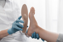 Orthopedic Insole On A White Background. Hands In Rubber Gloves Hold An Orthopedic Insole. Foot Care, Comfort For The Feet. Doctor Orthopedist Tests The Medical Device. Flat Feet Correction