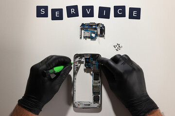 Wall Mural - Technician repairing broken smartphone at white table, top view