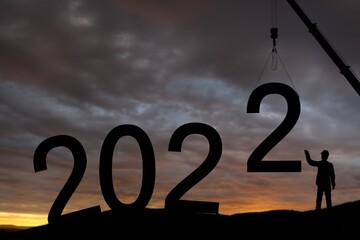 Wall Mural - Silhouette of construction worker with crane and sky for preparation of welcome 2022 new year party and change new business.