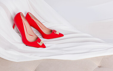 close up of woman red shoes placed on white silk cloth