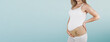 © mlphoto - Pregnant woman belly in prenatal pregnancy maternity belt isolated on blue background. Orthopedic abdominal support waist, back, abdomen band. Belly Brace for pregnancy. Horizontal banner or poster