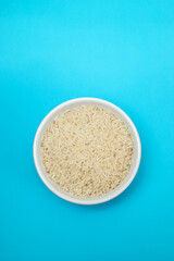 Poster - raw rice on white small bowl on blue