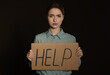 © New Africa - Unhappy young woman with HELP sign on dark background