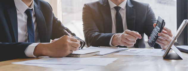 Business meeting, two caucasian, asian yong group man brainstorm analyzing on graph data of cost plan or document, paperwork and discussing in board room on table. People working conference room.