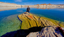 A hiker standing on a rock peninsula at Lake Powell, Arizona