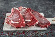 © mehmet - Fresh Raw Beef ribs roughly chopped. Marble beef meat on the bone ribeye.  Raw cowboy steak with seasoning on stone background, prime rib eye on bone, top view.