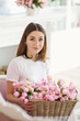 © Olena Serzhanova - Young woman sitting on sofa with basket of pink tulips.