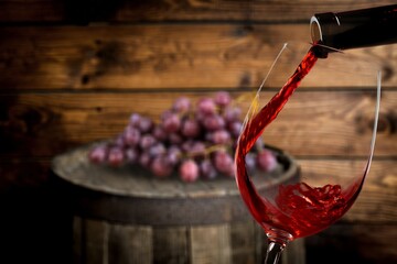 Sticker - Wine is poured into a glass. Red wine and grapes on a vintage background