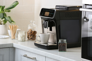 Poster - Modern electric coffee machine with cup on white countertop in kitchen