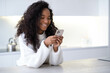 African American smiling Girl using smartphone on modern kitchen at home, pressing finger, reading social media internet, typing text or shopping online, Mobile phone in two black hands