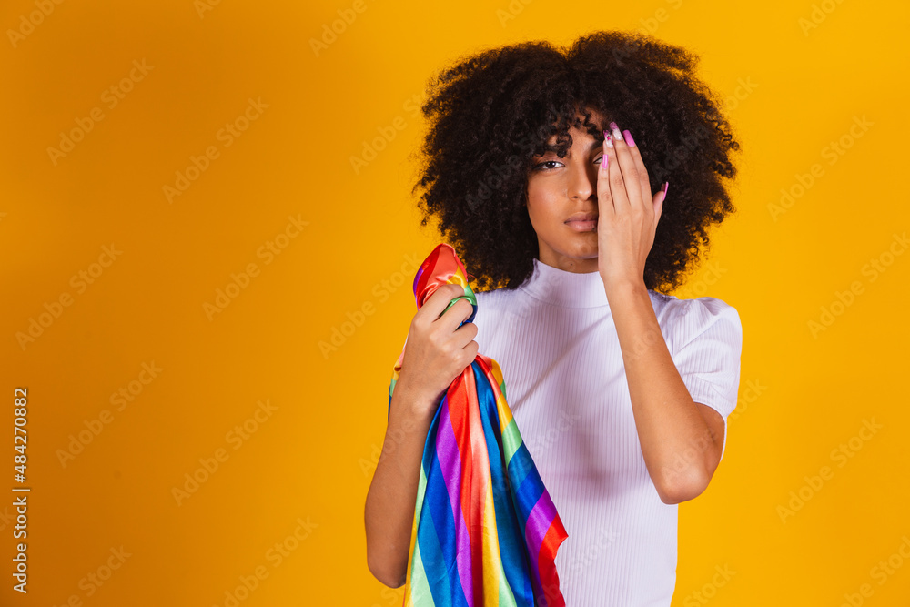 Afro woman with an lgbt flag in her hands covers half of her face with ...
