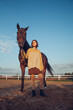 A young girl with a short haircut next to her horse at sunset. Good friends. Summer and happiness.