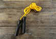 Skipping rope on wooden table, top view. Sports equipment