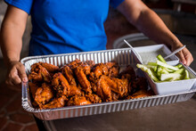 Server Holding Large Tray Of Buffalo Wings With Celery And Blue Cheese