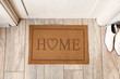© Pixel-Shot - Stylish mat with word HOME near light wooden door in hallway